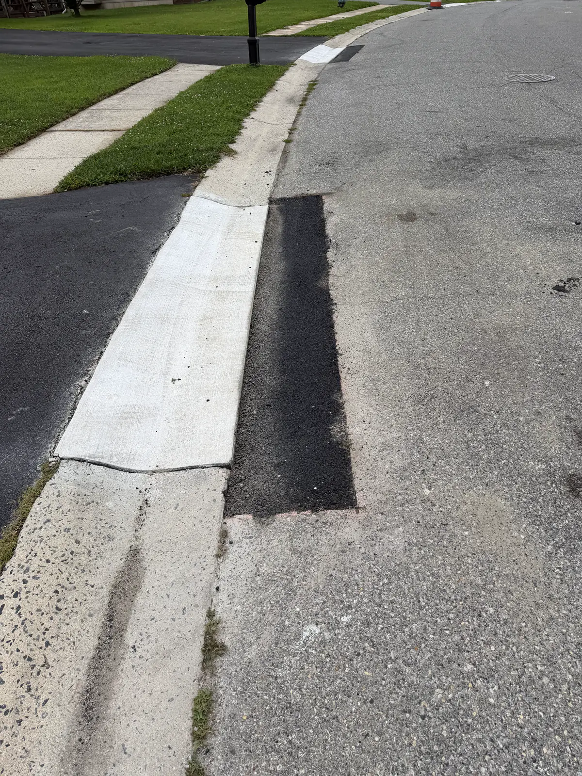 Replaced concrete curb section with a fresh asphalt patch at the gutter line in New Castle County, DE