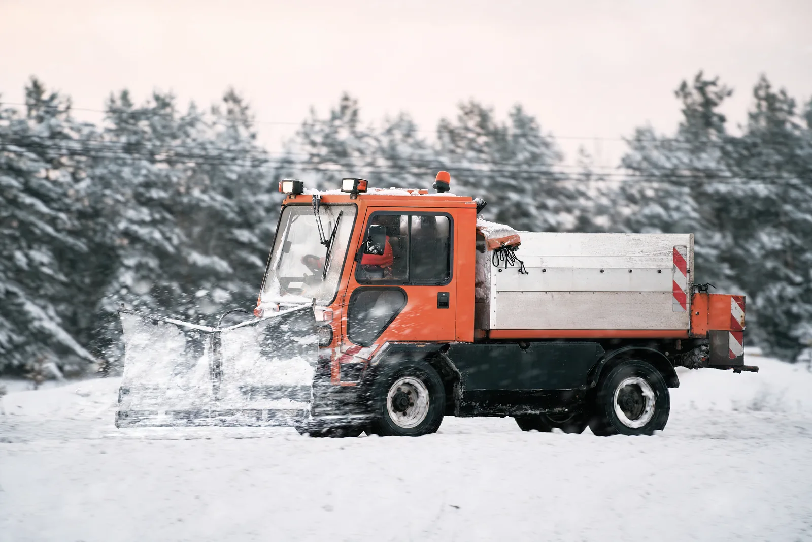 Salt and sand spreader treating an icy surface during winter snow removal